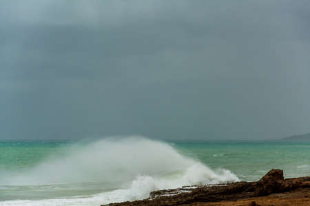 angry turquoise green color massive rip curl of a waves as it barrel rolls along the ocean.