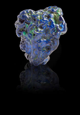 Blue and green Azurite gemstone with ground reflection on the black background