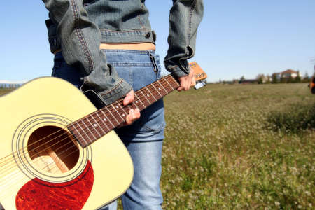 A woman holding a guitar looking at an empty fieldの写真素材