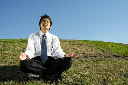 A businessman meditating in a parkの写真素材