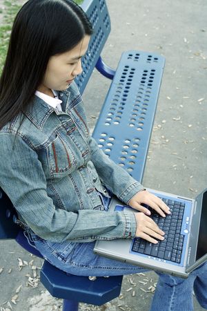 A girl working on her laptop at a parkの写真素材