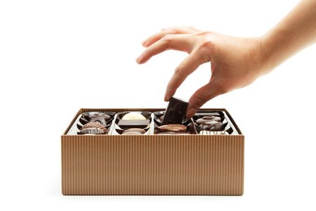 A woman's hand choosing a chocolate from a boxの写真素材