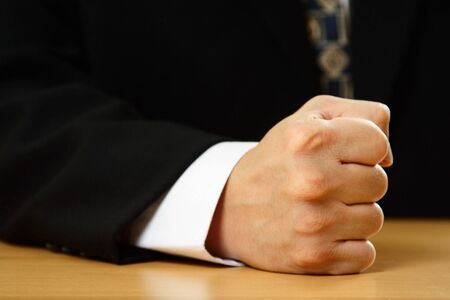 A businessman with his firm fist on a tableの写真素材