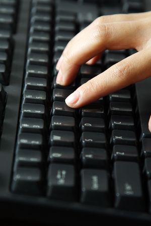 A businesswoman typing on a black keyboard
