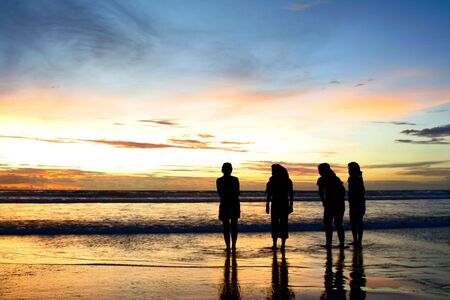 Silhouette shots of four girls on the beach enjoying the dramatic sunsetの写真素材
