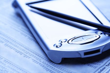 A PDA and a newspaper showing financial dataの写真素材