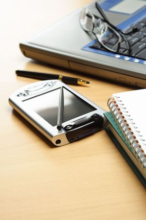 A laptop, PDA and a notebook in business office environment settingの写真素材