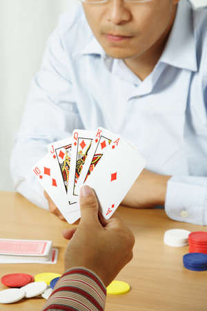 A shot of two young men playing poker with one holding winning cards のeditorial素材