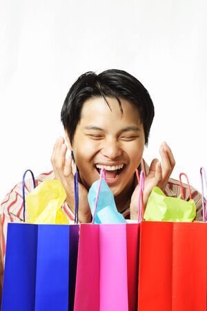 An isolated shot of a happy young man with shopping bagsの写真素材