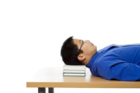 An isolated shot of a businessman sleeping on a table using books as the pillowの写真素材