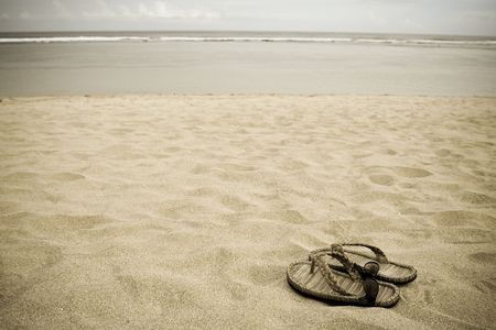 A pair of sandals and sunglasses on a serene beachの写真素材
