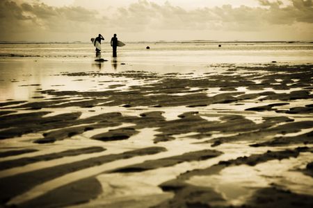 Two surfers at the beach during sunsetの写真素材