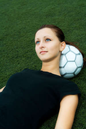 A beautiful soccer player resting on a soccer ballの写真素材