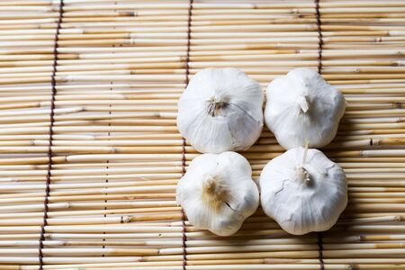 A shot of four garlics on a bamboo matの写真素材