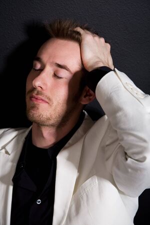 A shot of a stressed caucasian businessman leaning against a black wall