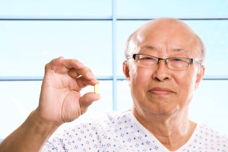 A shot of a senior asian man holding a pillの写真素材