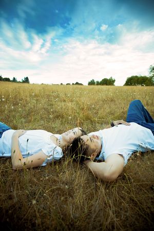 A shot of an asian couple in love lying down on grass under the blue skyの写真素材