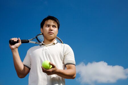 A young asian male tennis player outdoorの写真素材