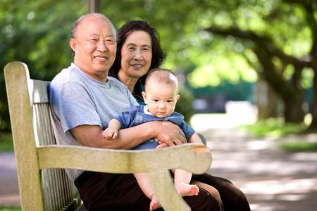 A shot of a cute asian child with his grandparents in a park