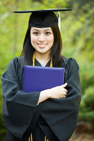 A happy beautiful graduation girl holding her diplomaの写真素材