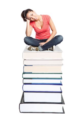 An isolated shot of a beautiful black college student sitting on a stack of booksの写真素材