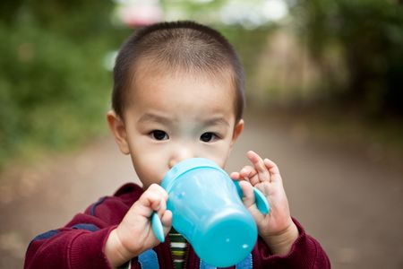 A portrait of an asian boy drinking from his cupの写真素材