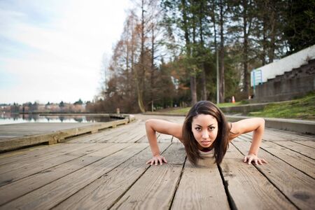 A shot of a beautiful black woman doing push up outdoorの写真素材