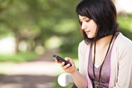 A shot of a mixed race girl texting on the phone at campusの写真素材