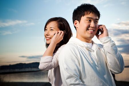 A portrait of an asian couple talking on the phoneの写真素材