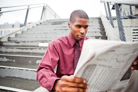 A portrait of a black businessman reading newspaper outdoorの写真素材