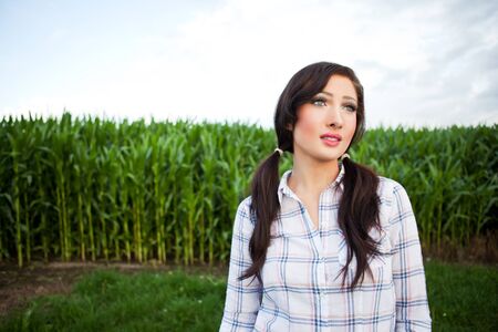 A shot of a beautiful farm girl near the corn fieldの写真素材