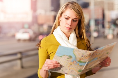 A shot of a beautiful caucasian traveling woman reading a mapの写真素材