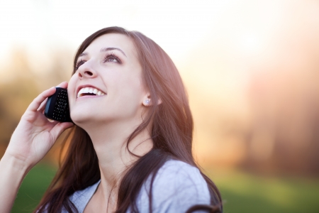 A portrait of a smiling beautiful woman talking on the phoneの写真素材