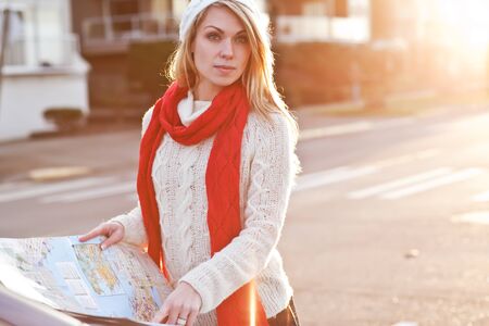 A shot of a beautiful caucasian traveling woman reading a mapの写真素材