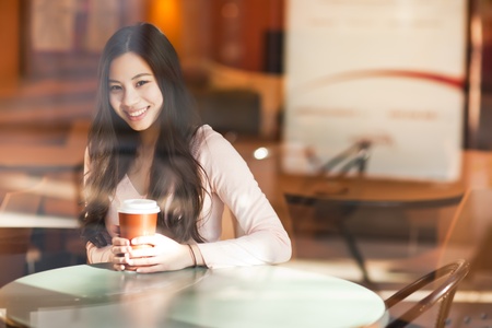 A shot of a beautiful asian woman drinking coffee in a cafeの写真素材