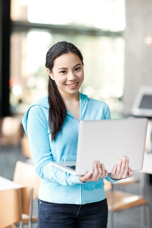 A shot of an Asian college student working on her laptop on campusの写真素材