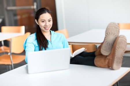 A shot of an Asian college student working on her laptop on campusの写真素材