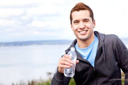 A shot of a mixed race man holding water bottle outdoorの写真素材