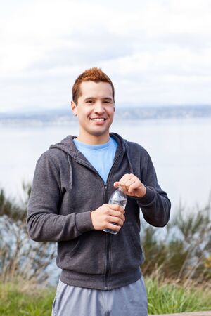 A shot of a mixed race man holding water bottle outdoorの写真素材