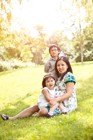 A shot of a pregnant Asian mother with her two kids outdoorの写真素材