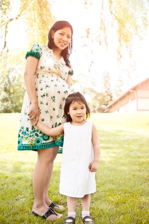 A shot of a little Asian girl and her pregnant motherの写真素材