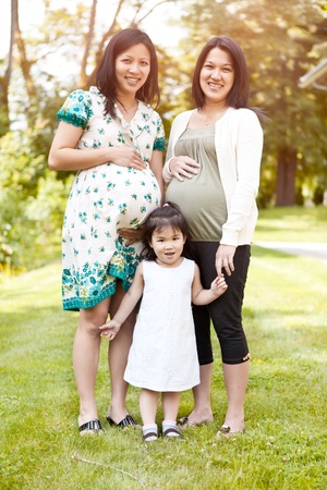 A shot of two beautiful pregnant Asian women and a little girlの写真素材