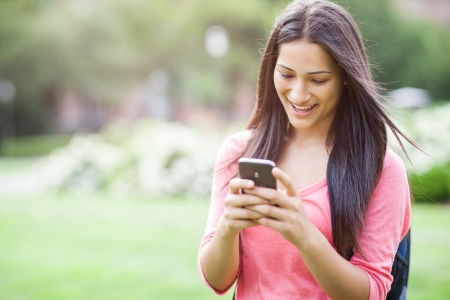 A beautiful hispanic college student texting on her cellphoneの写真素材