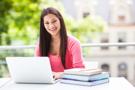 A shot of a hispanic college student working on laptop at campusの写真素材