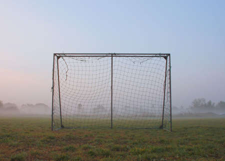 Old soccer goal on a playground in a misty landscapeの写真素材