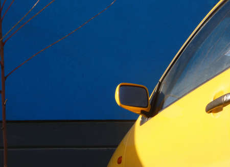 Yellow car in front of a blue wallの写真素材