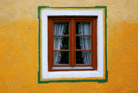 Wooden window in a yellow wall of an old house の写真素材