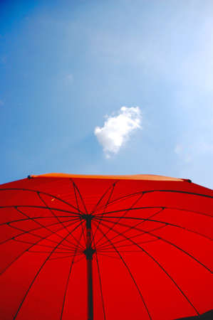 Red parasol with a single cloud in a blue sky