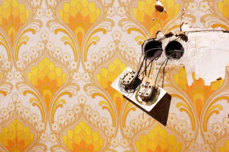 Old wallpaper with loose power socketの写真素材