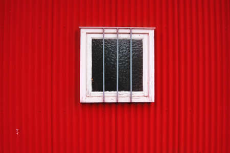 Red wall and white window with anti-theft protectionの写真素材